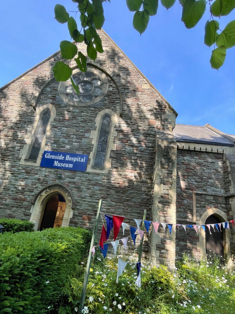 Glenside Hospital Museum in Fishponds, exterior picture shown with party bunting in the sun, during free walking tour. Museum of mental health care exploring the history of Glenside Hospital in Fishponds, Bristol.