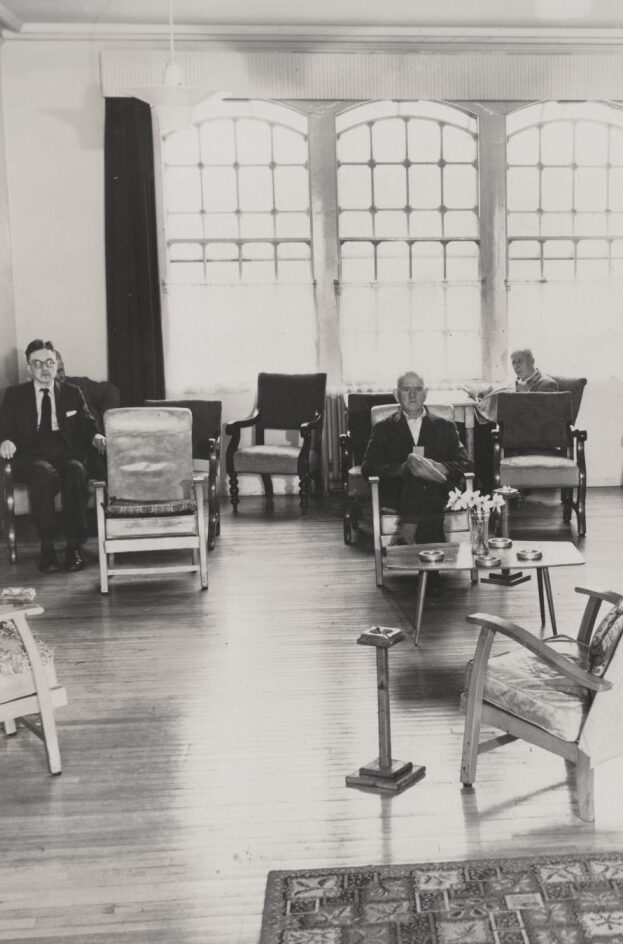Men sitting still in a day room at Glenside Hospital, originally a Victorian asylum