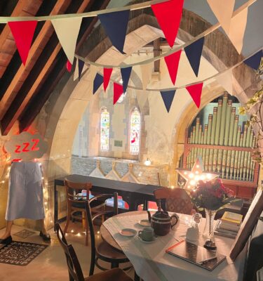 Tea in the Turret at Glenside Hospital Museum, a cosy balcony room with colourful bunting and a table set for afternoon tea, with teapot, tea cups and plates